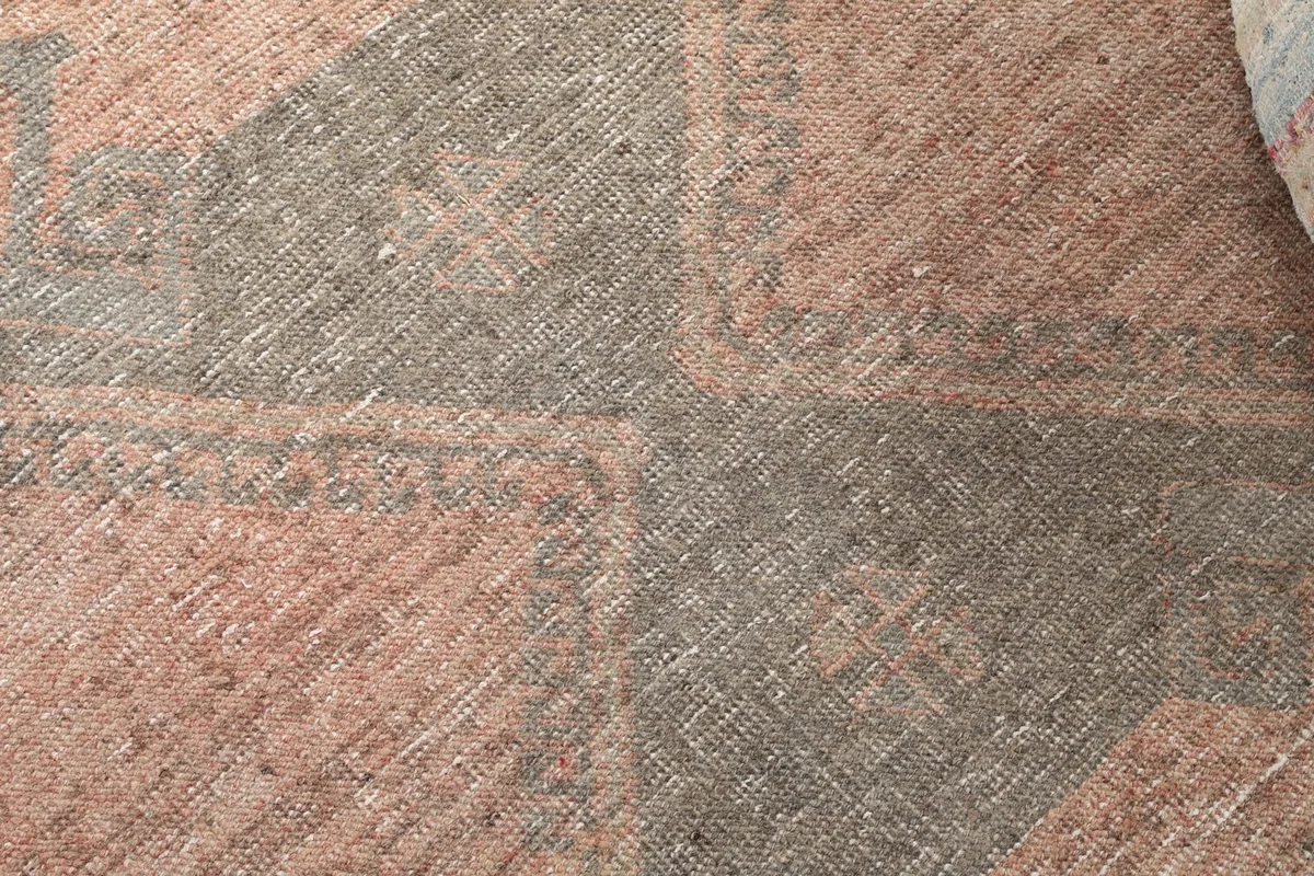Close-up of the hand-knotted wool pile, showing the texture and colors of the geometric pattern.
