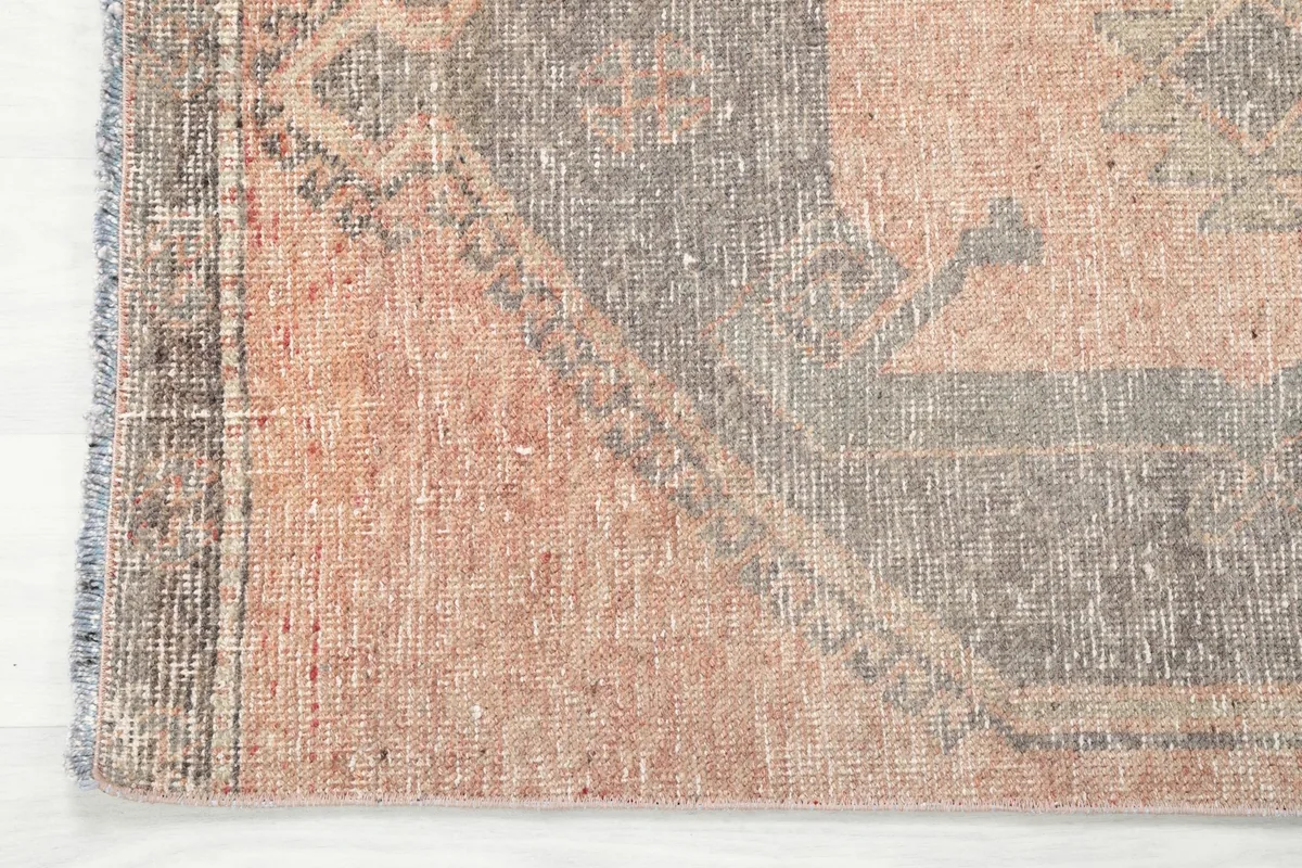 Detail of the rug's edge and fringe, showcasing the subtle color variations and hand-knotted craftsmanship.