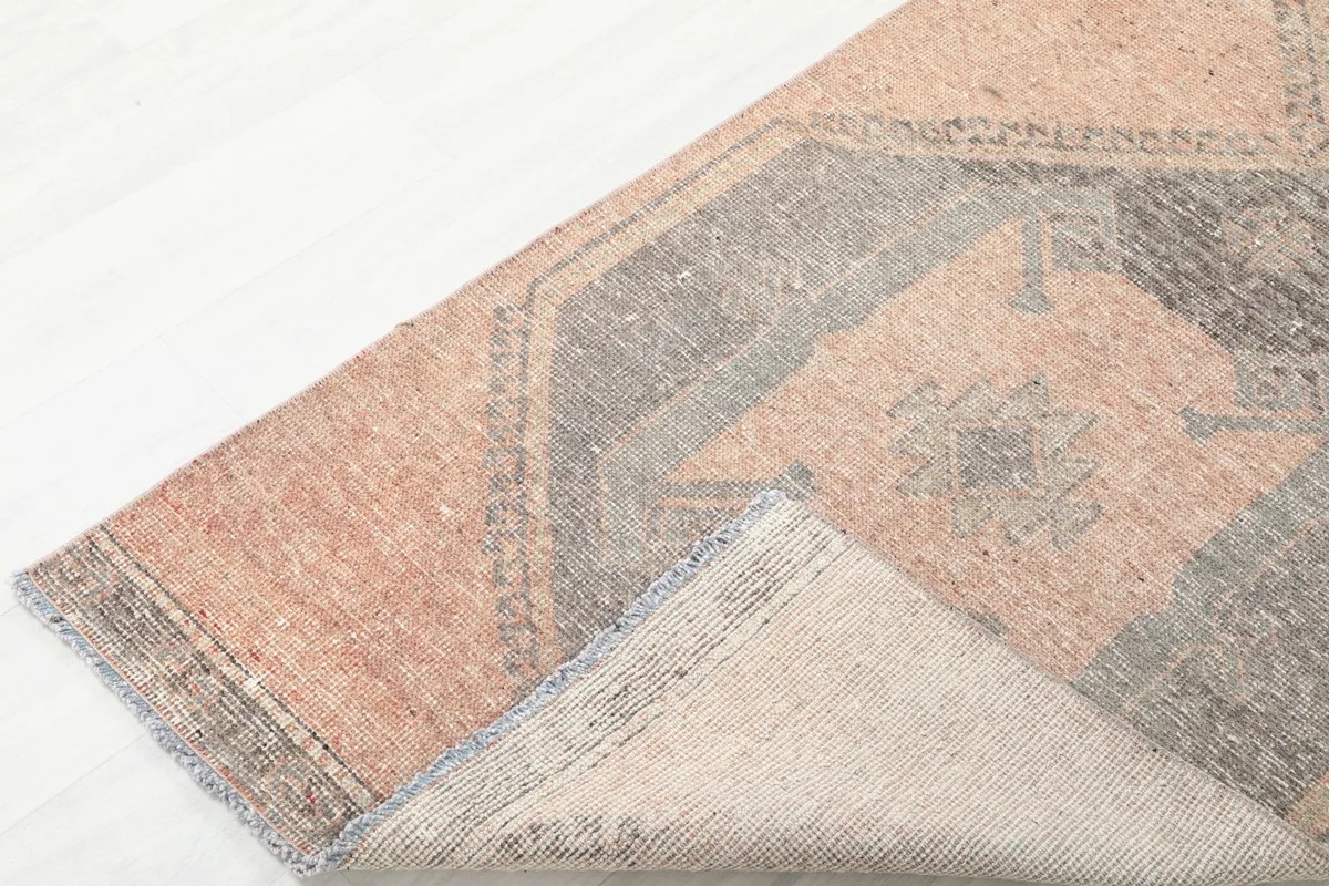 Corner of the runner rug folded back to reveal the cotton foundation and reverse side.
