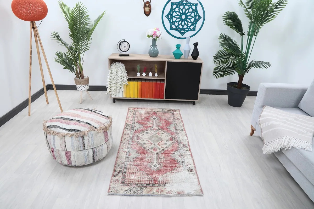 Vintage red and beige rug placed in a modern living space with a sofa and ottoman