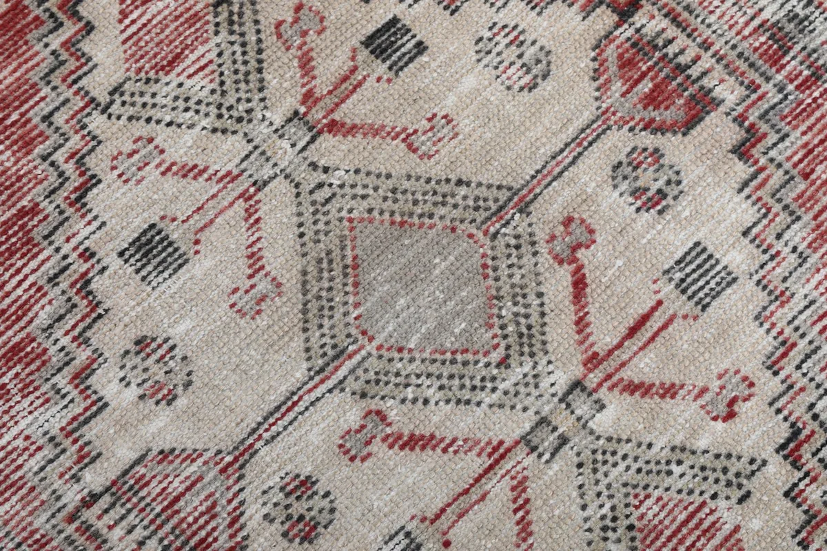 Detailed close-up of the beige central medallion with intricate gray and red geometric elements