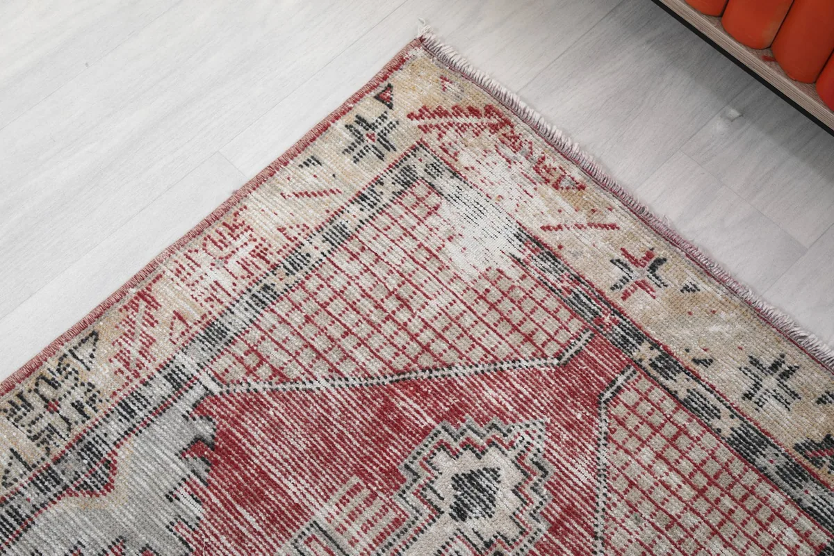 Corner detail showing the distressed beige border and geometric patterns in red and black