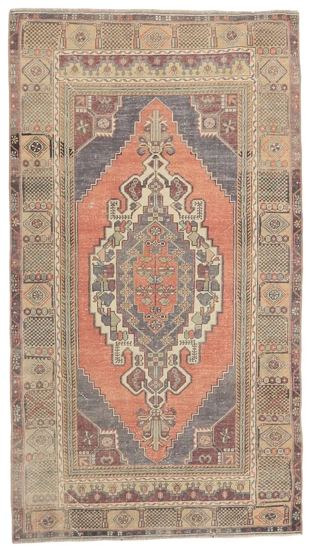 Full overhead view of a vintage rust and gray medallion Anatolian rug on a white background