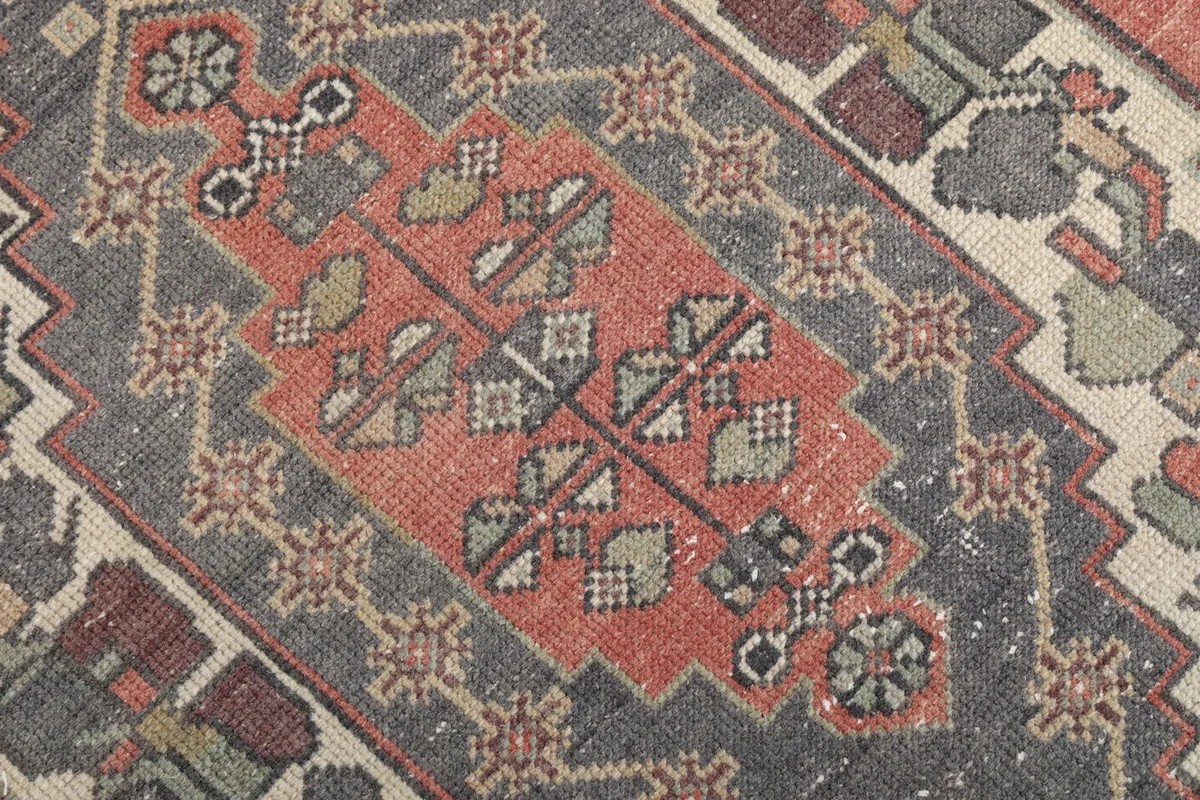 Close-up of the intricate patterns within the gray medallion and rust field of the rug