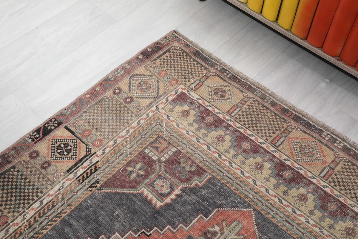 Detailed corner view of the rug, showing the layered geometric borders in beige, brown, and gray