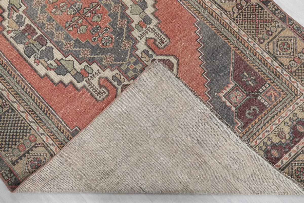 Corner of the rug folded back to reveal the cotton foundation and hand-knotted construction