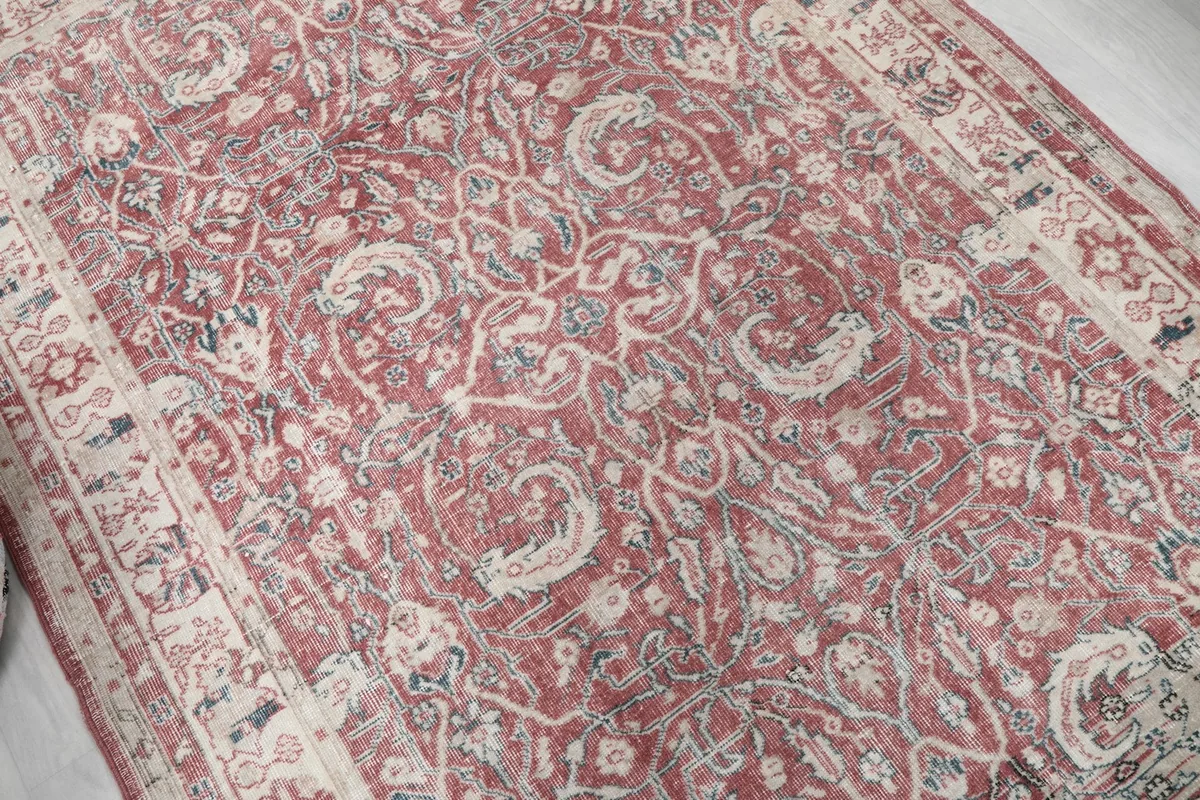 Close-up of the rust field with detailed floral and vine motifs in cream and blue.