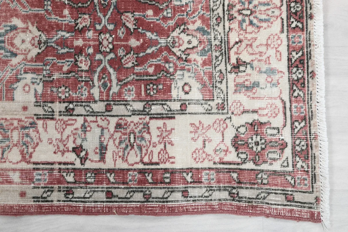 Detail of the rug's corner, showcasing the cream border with rust and blue accents.