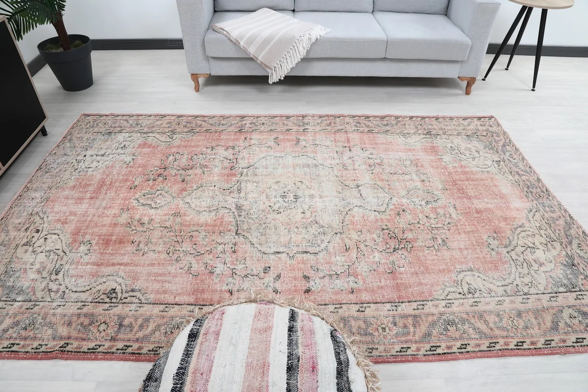 Overhead view of the rug in a living room setup, with a round ottoman in the foreground