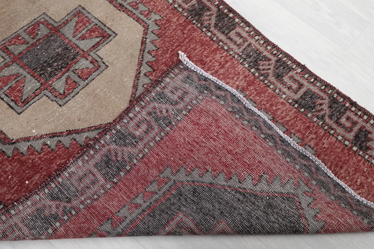Corner of the rug folded back, revealing the hand-knotted cotton foundation and wool pile.