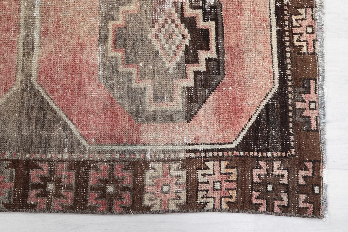 Detailed view of the rose and brown geometric medallion and the border pattern