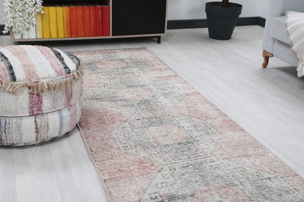 Close-up angle shot of the runner rug, highlighting its rose and gray geometric patterns near a pouf.