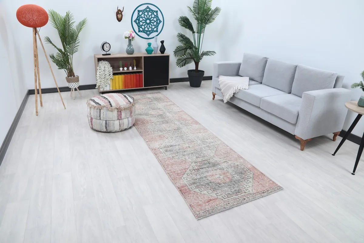 Angle view of the rose and gray geometric runner rug laid out in a contemporary living space.