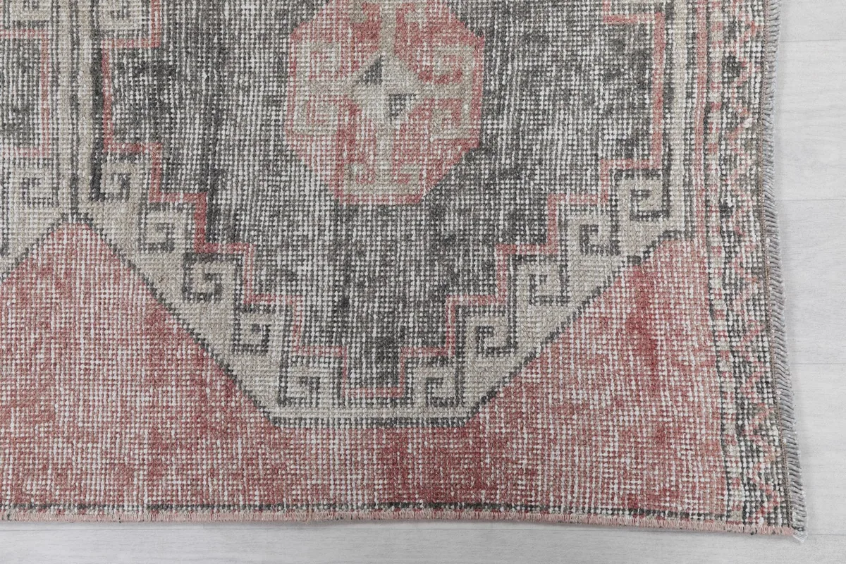 Detailed view of the geometric patterns and border on the vintage Anatolian runner, showing wear.