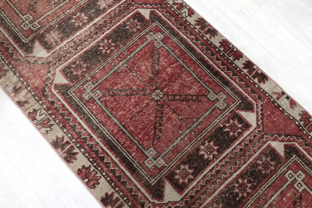 Angled shot highlighting the central geometric medallions and the distressed red and brown colors.