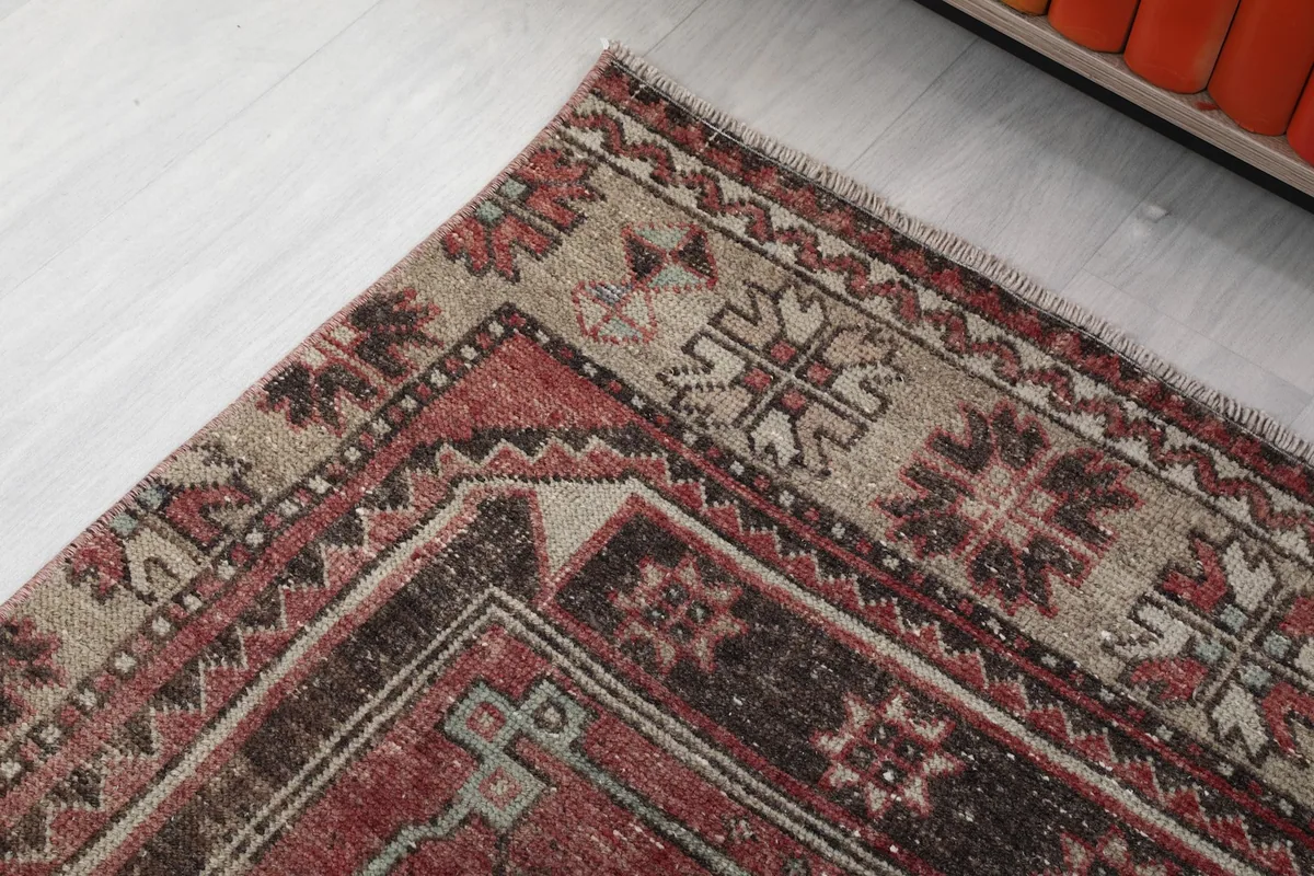 Detail of the rug's border design, showcasing tribal motifs in beige, brown, and red tones.