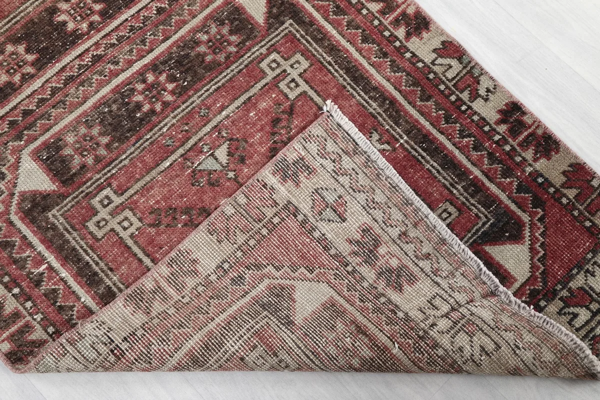 Corner of the rug folded back to show the cotton foundation and hand-knotted construction.