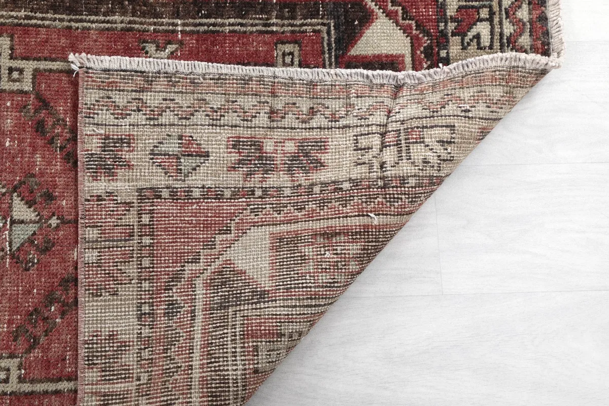 Underside view of the rug's corner, revealing the tightly woven cotton foundation and fringe.