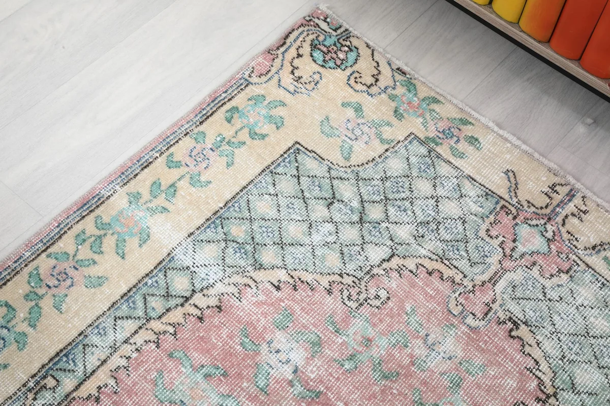 Detail of the upper left corner of the rug, showing the ivory border and green patterns