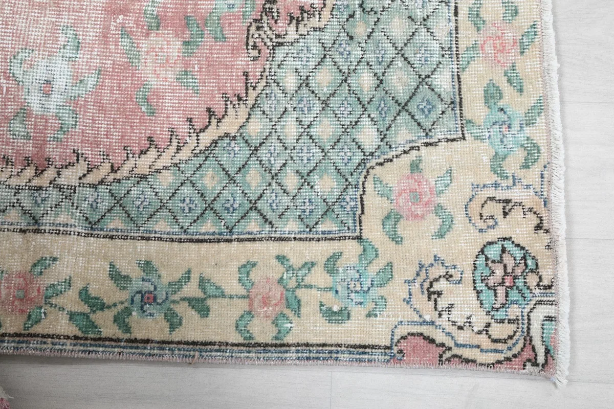 Detail of the rug's ivory border with floral motifs and the green geometric inner border