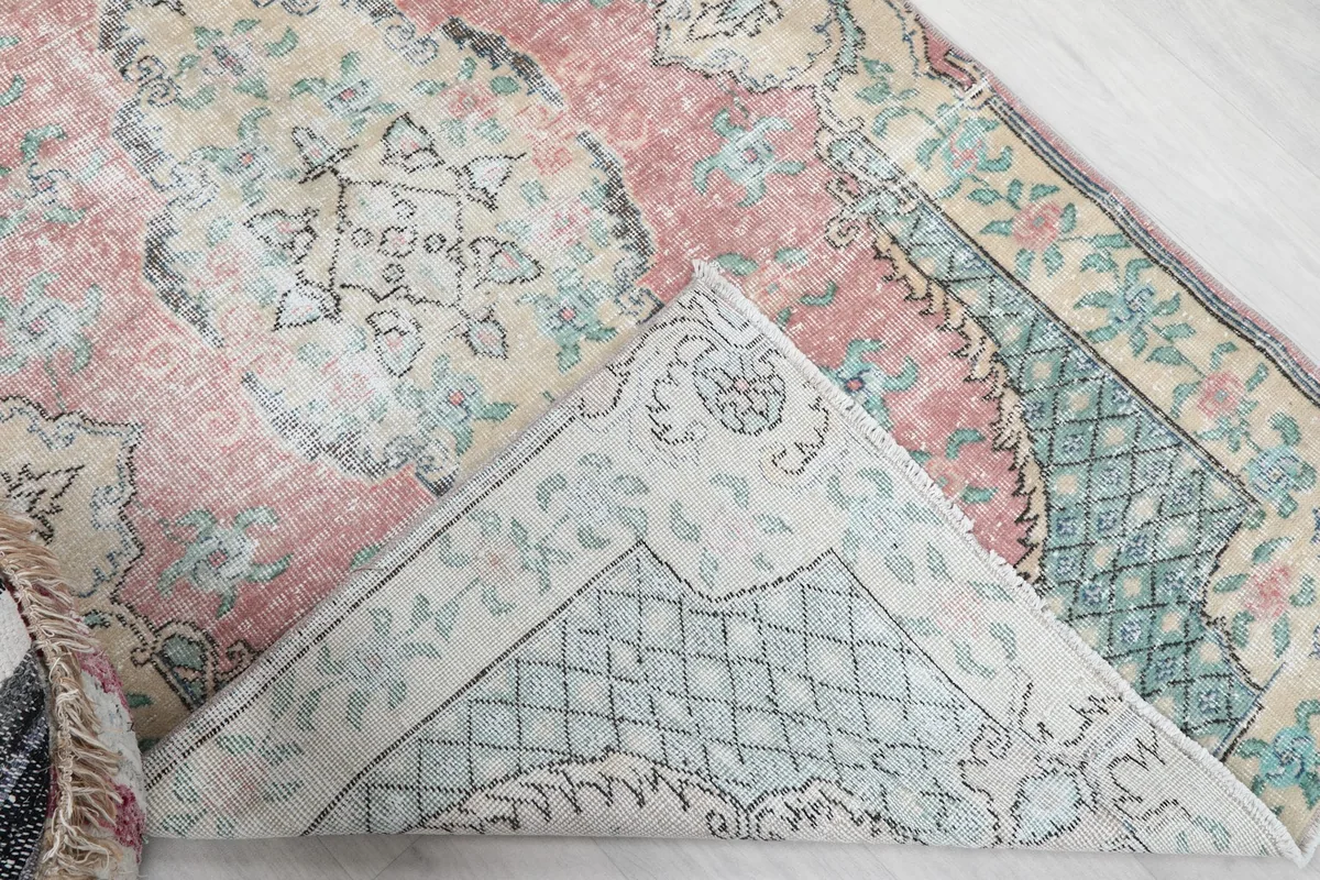 Corner of the rug folded back to show the back of the hand-knotted cotton foundation and wool pile