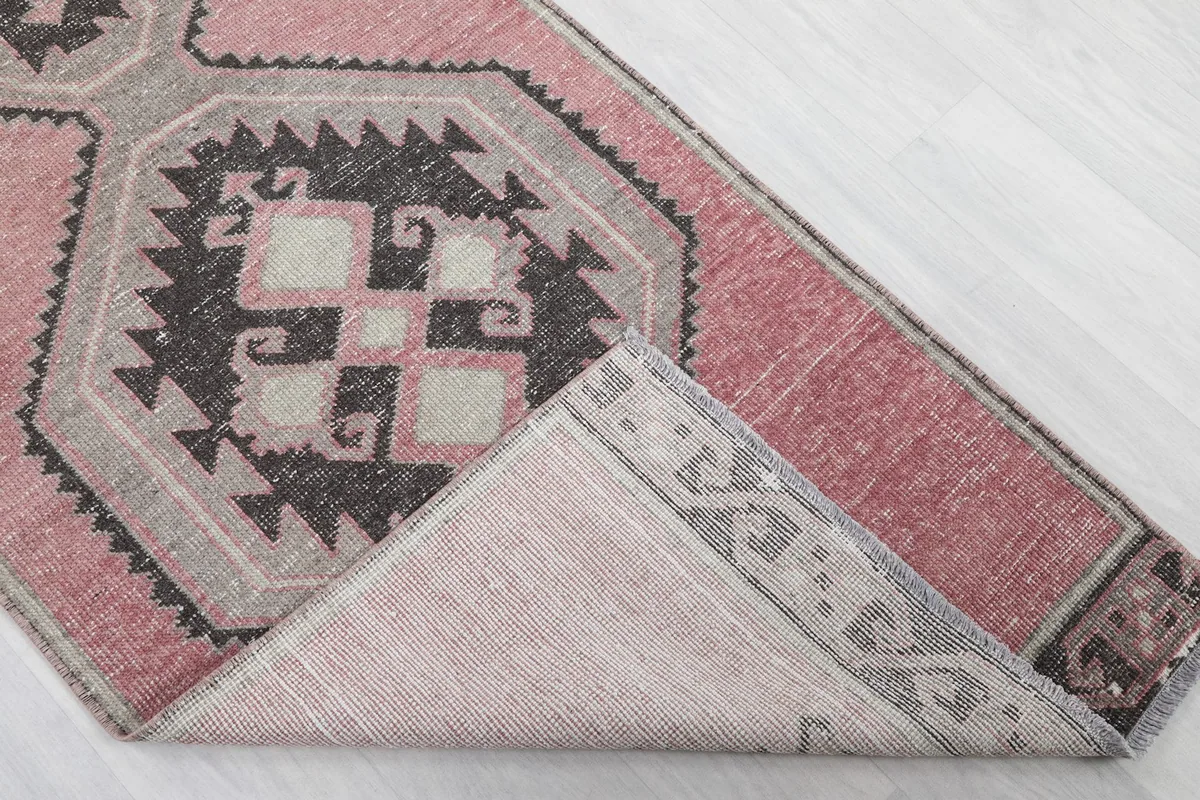 Corner of the rug folded back to reveal the cotton foundation and reverse side