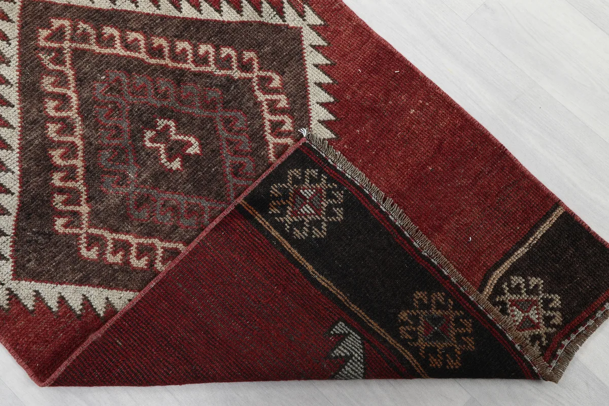 Rustic Red Tribal Diamond Runner, folded corner revealing the cotton foundation and hand-knotted back
