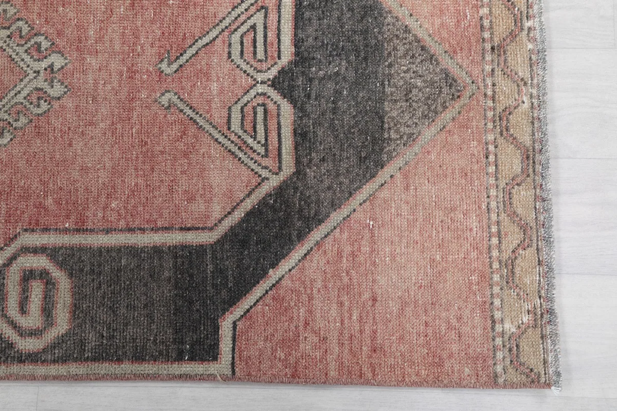 Close-up detail of the rug's border and a section of the charcoal geometric design.