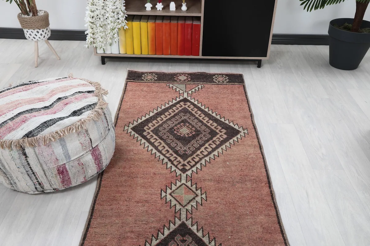 Overhead view of the rose runner rug in a room, showing its alignment with a cabinet and ottoman