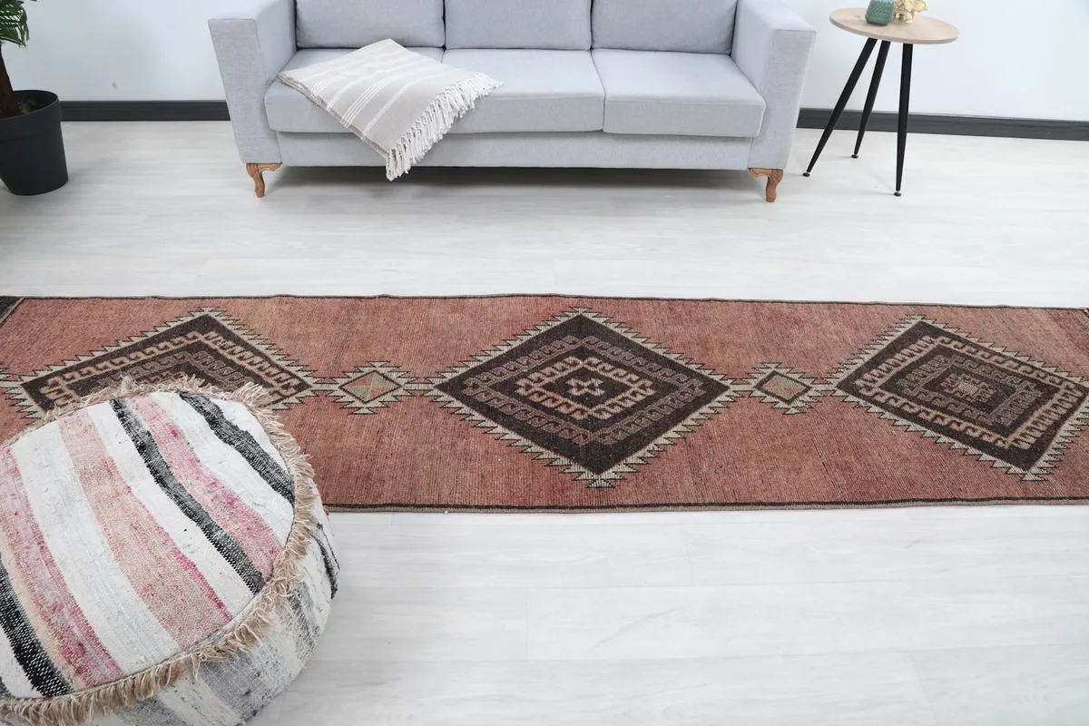 Full length view of the rose runner rug in a room, positioned between an ottoman and a sofa
