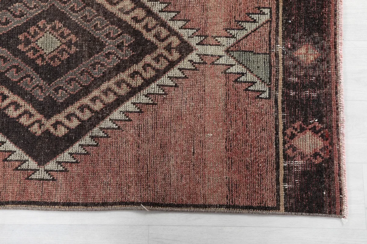 Detailed view of the rug's border and one end, highlighting the rose field and pattern elements