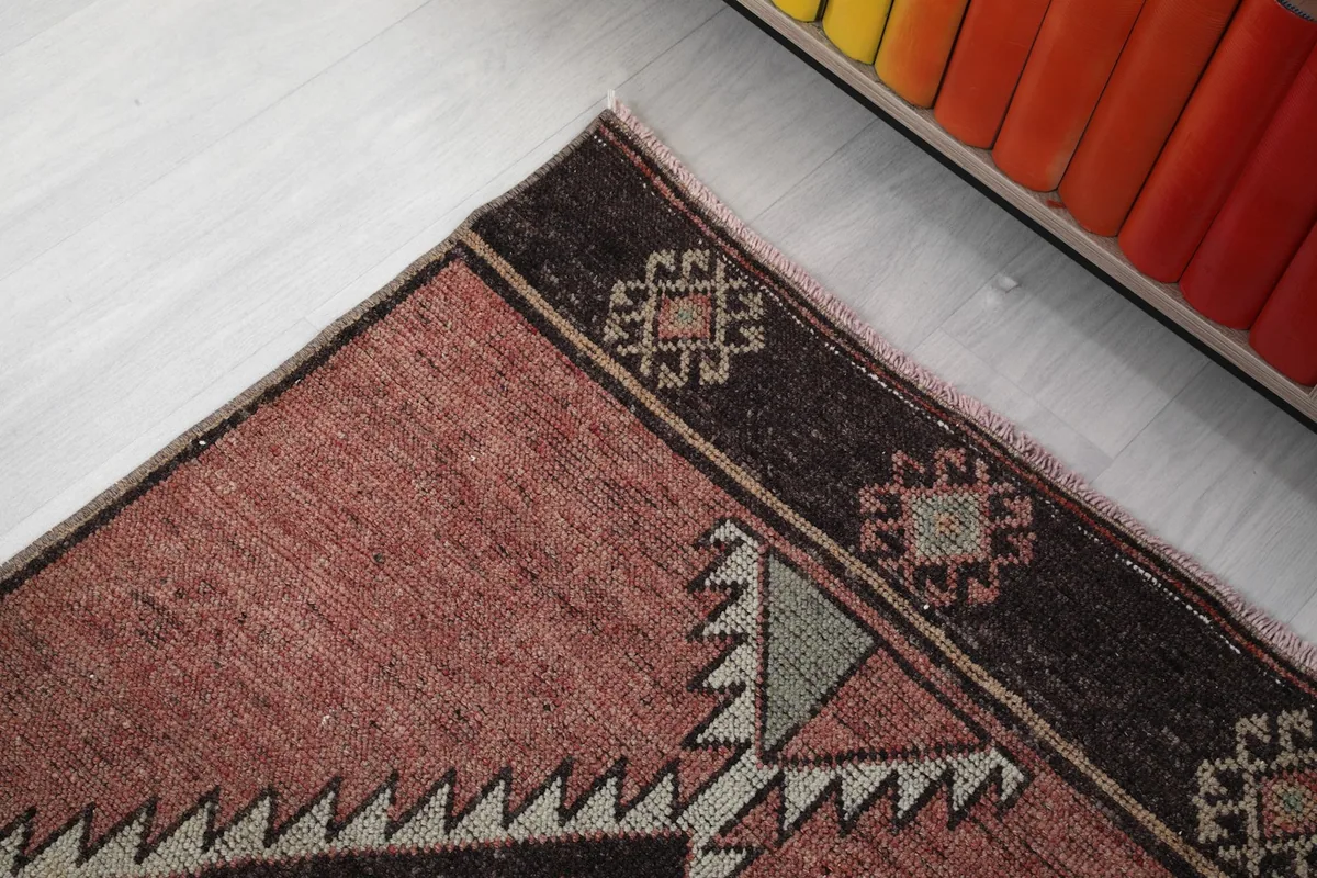 Detail of the rug's top border with small geometric designs and the faded rose field