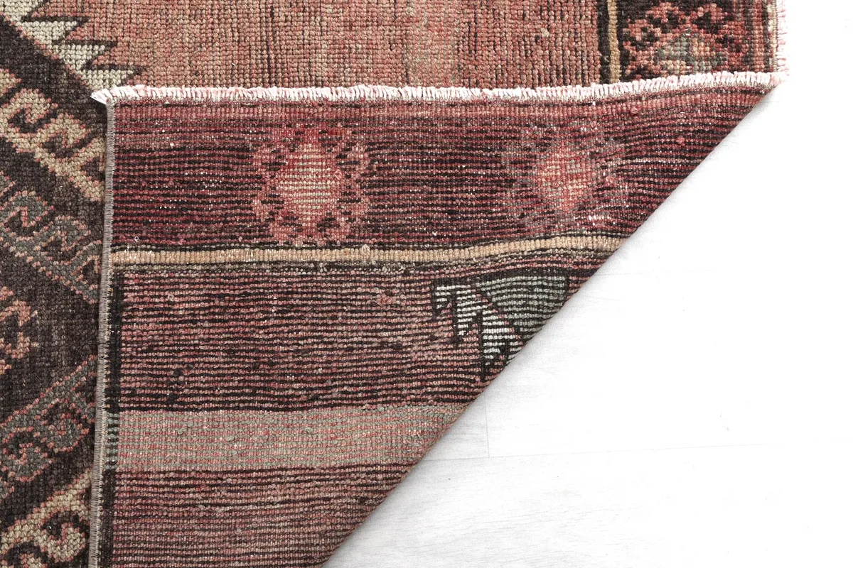 Close-up of the rug's back, revealing the weave structure and the colors of the foundation