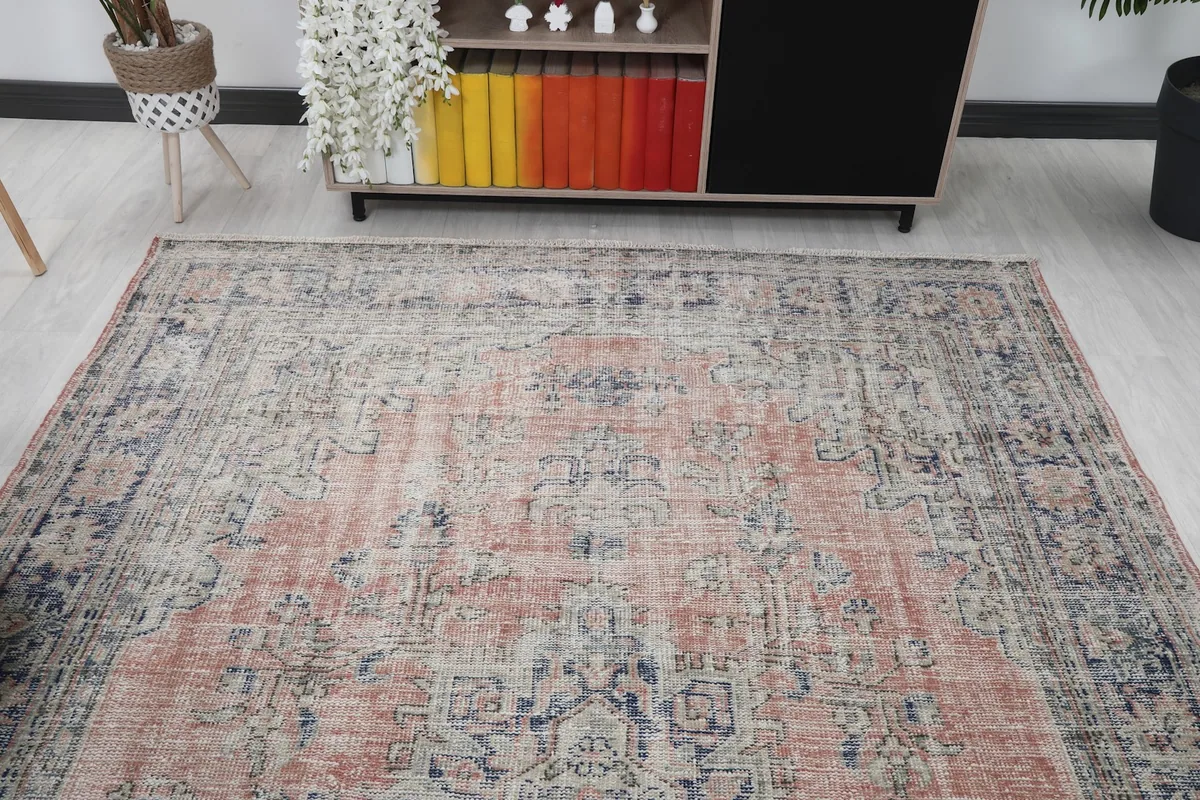 Room view showing the rug's placement near a bookshelf, highlighting the rust and navy color palette.