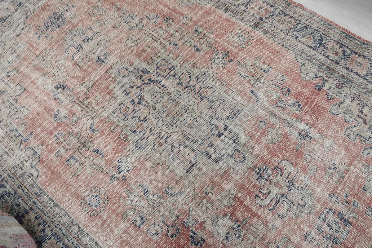 Overhead detail of the central medallion, showing the faded rust and navy intricate patterns of the rug.