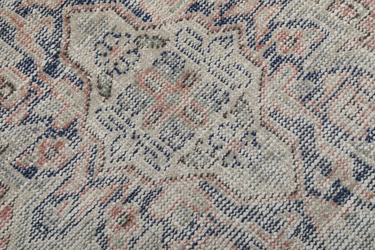 Close-up of the low wool pile, revealing the knotting and distressed texture of the rust and navy fibers.