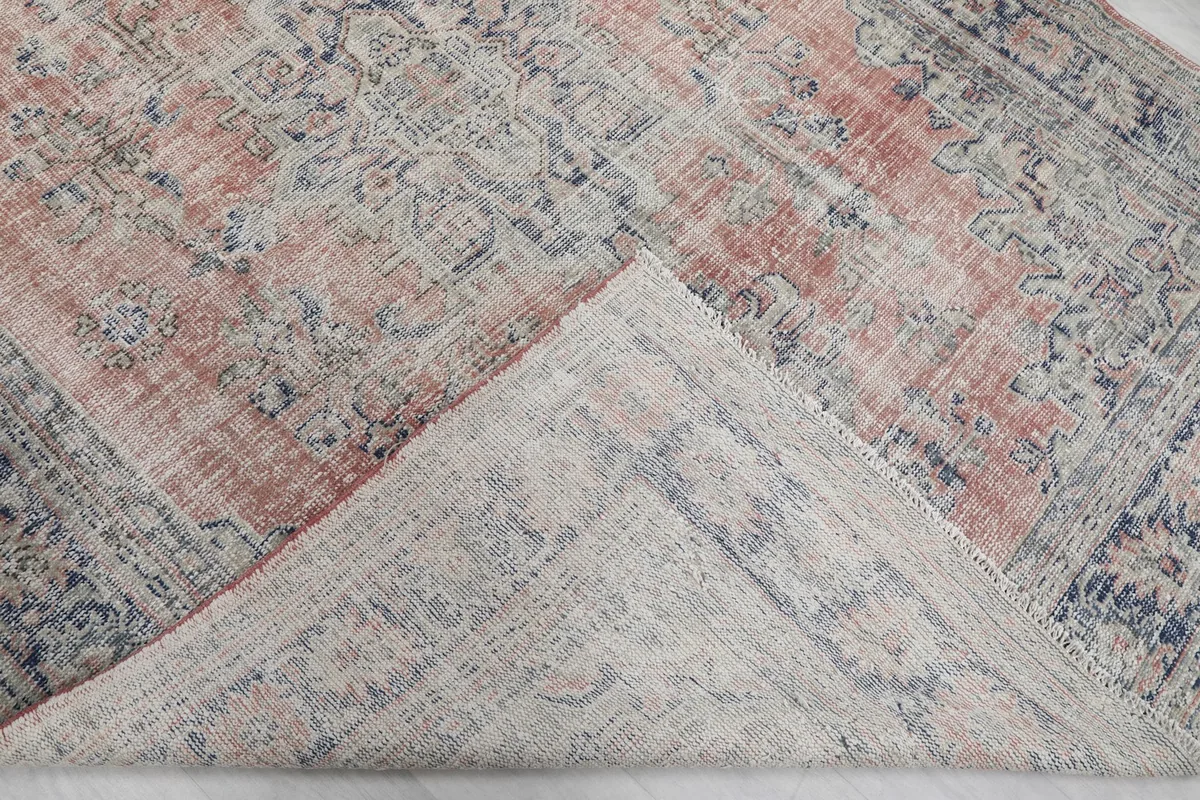 Folded corner of the rug revealing the cotton foundation and the reverse side of the hand-knotted wool pile.