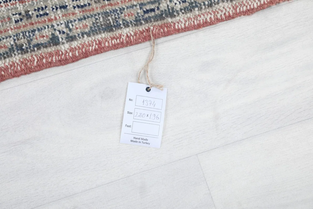 Product tag attached to the rug, showing its origin and dimensions, on a light-colored floor.