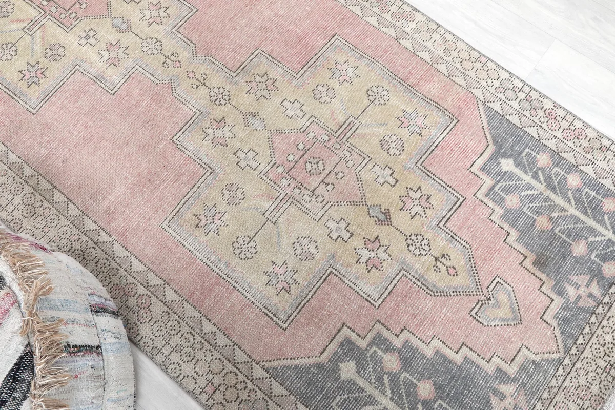 Overhead angle showing the central beige medallion and pink field of the rug