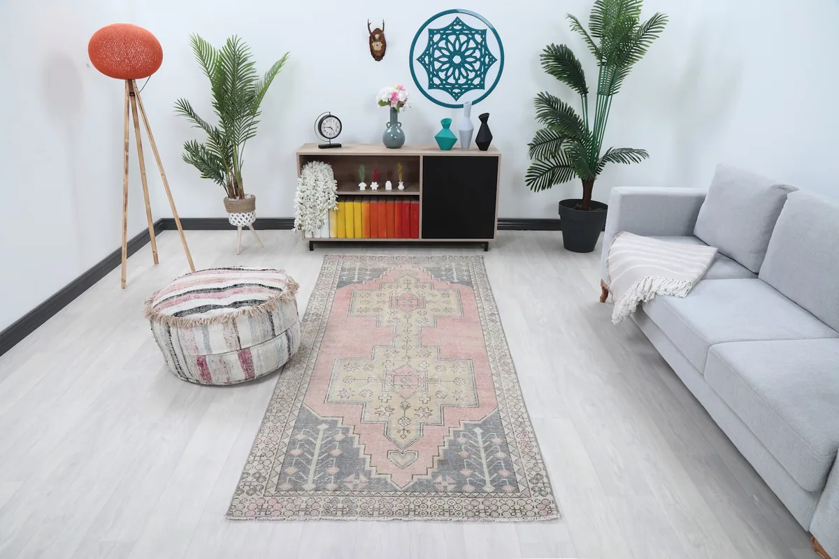 Vintage pink and beige rug styled in a living room setting with a light gray couch