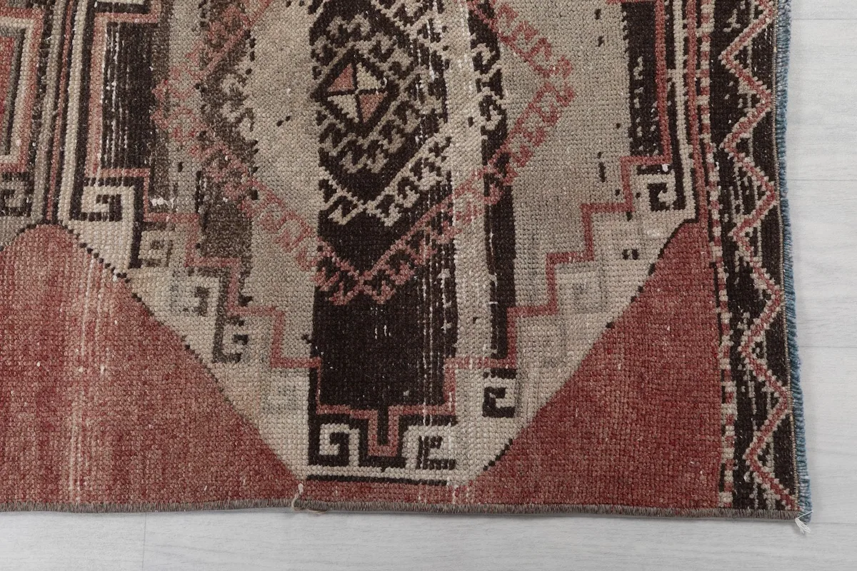 Detailed view of the geometric patterns and colors on one end of the rose runner rug