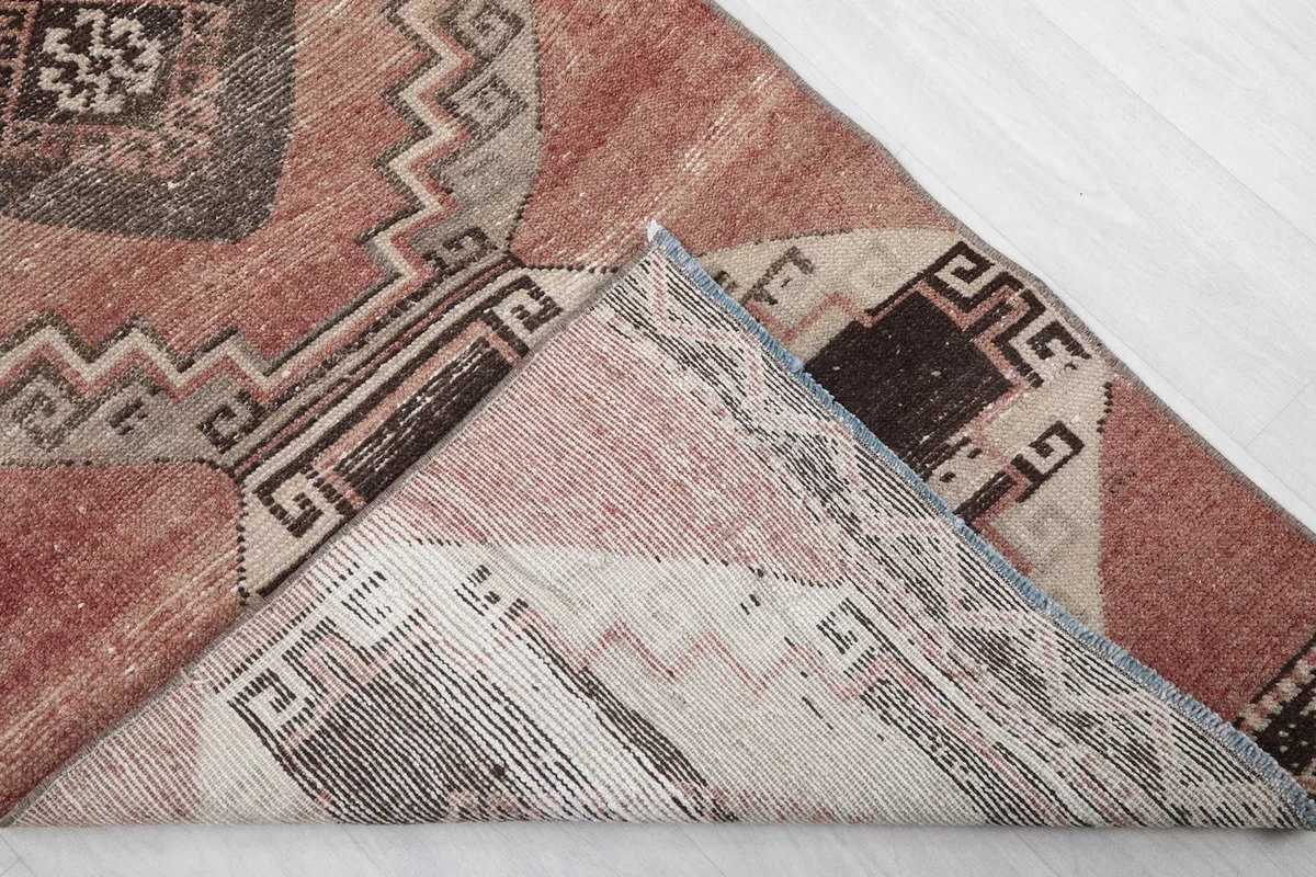 Folded corner of the rose runner rug revealing the back of the hand-knotted cotton foundation