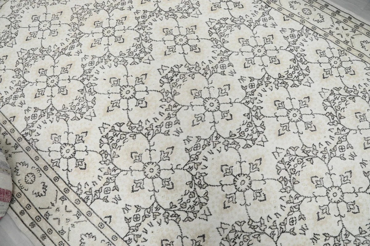 Close-up of the rug's central field, showing the repeating gray floral motifs and wool texture