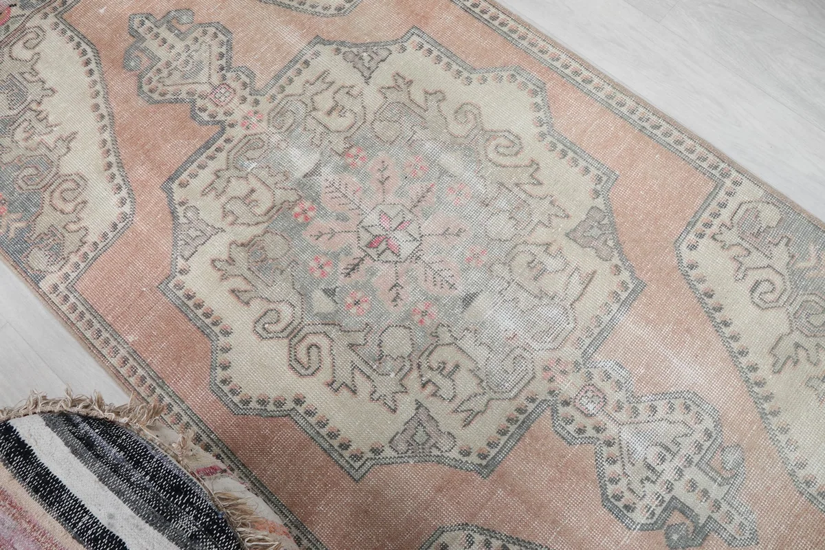 Overhead angle focusing on the central beige medallion and the distressed rose background.