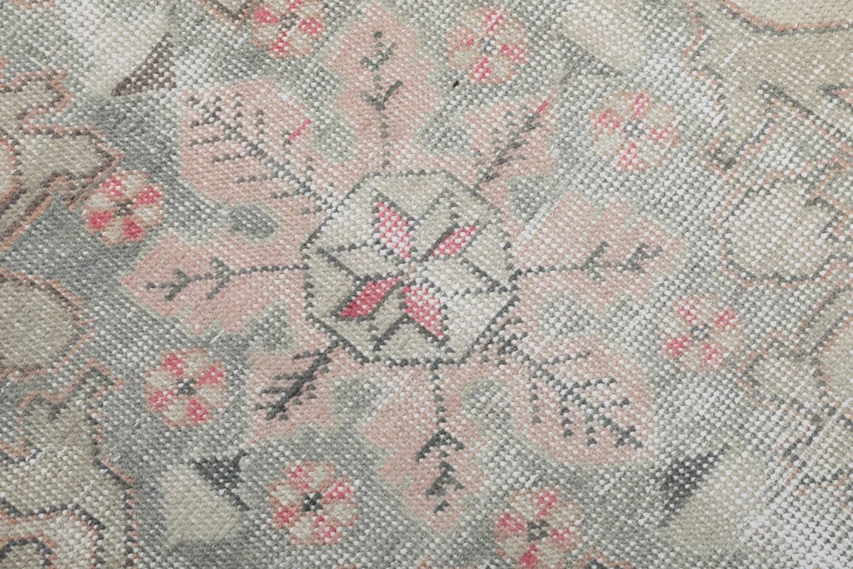 Close-up of the central medallion design, highlighting faded rose and gray geometric patterns.