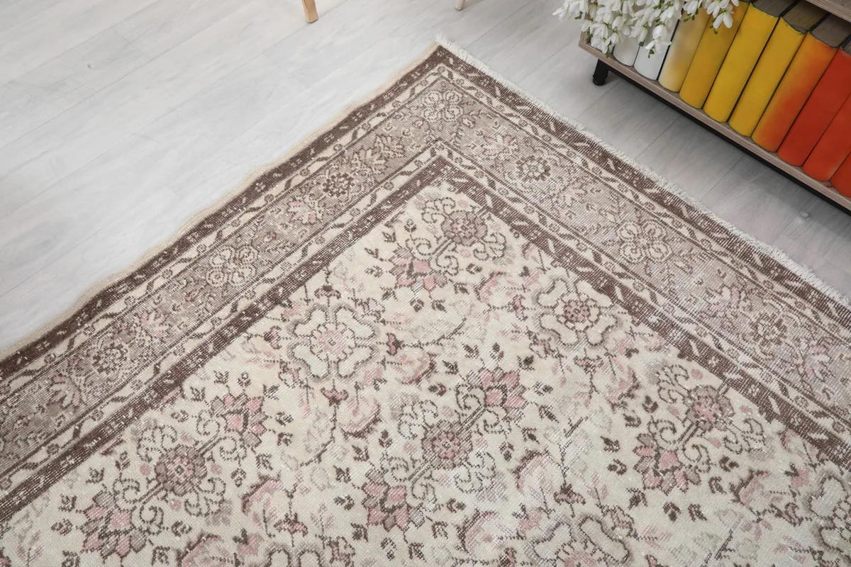 Angled shot highlighting the rug's faded brown border and the soft transition to the ivory center.