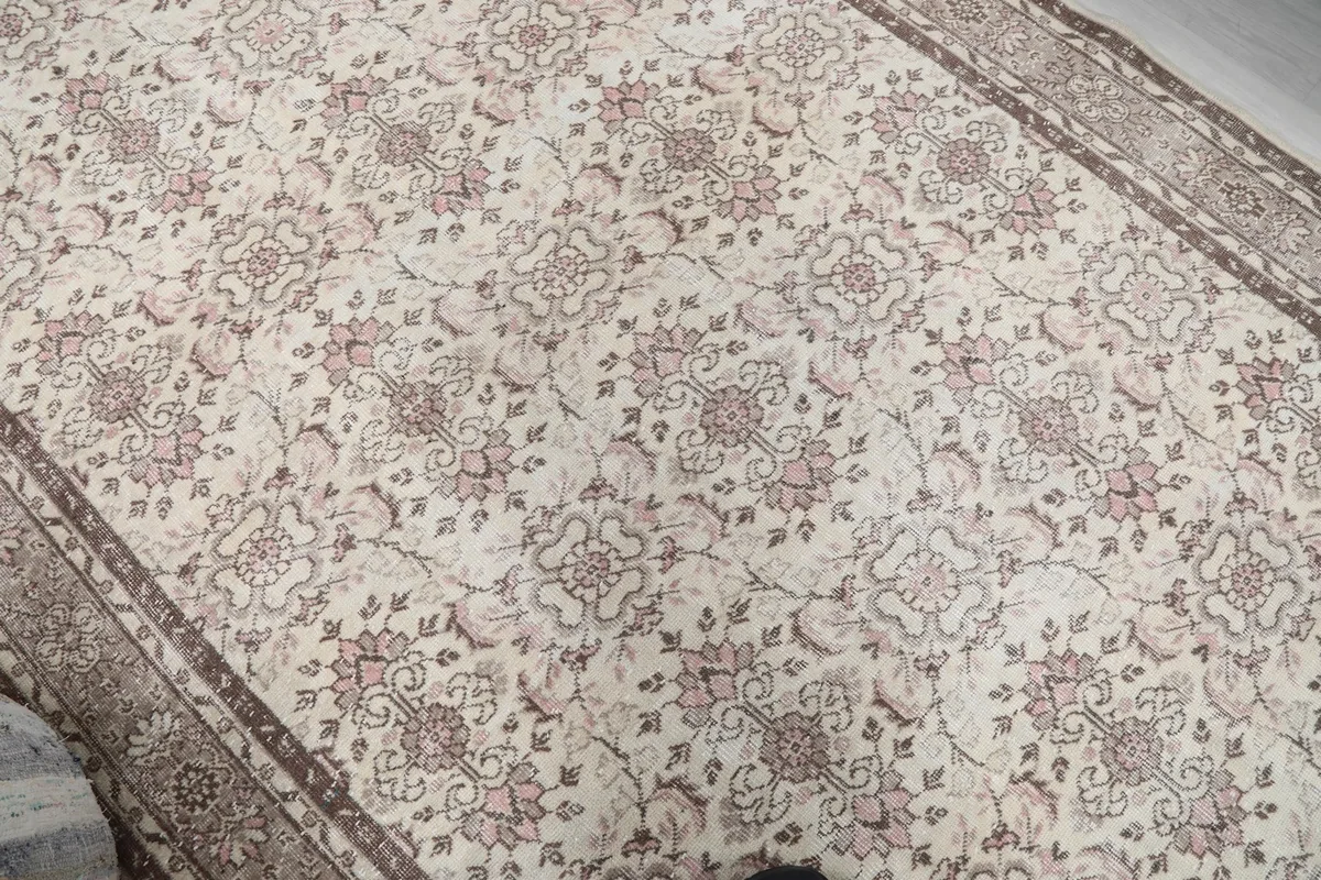 Overhead view showcasing the repeating rose and beige floral motifs across the rug's ivory field.
