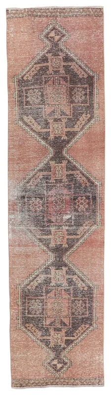 Full overhead view of the vintage rose and brown geometric tribal runner rug on a white background.