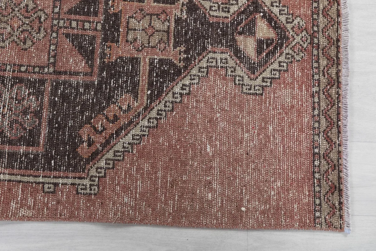 Detailed view of the corner of the runner rug, highlighting the rose color and subtle wear.
