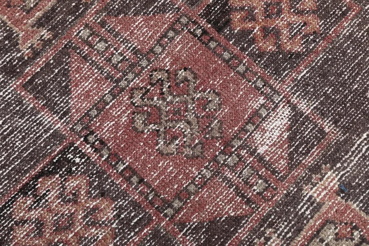 Macro detail of the hand-knotted wool pile, showing the texture and color variations within the brown motif.